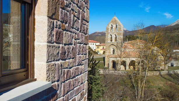 Edifici de pedra amb una finestra i vistes a l'església i al seu campanar.