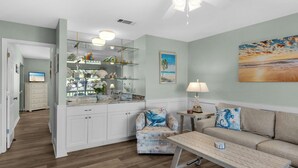 A living room with a ceiling fan, a sofa, a coffee table, and a kitchen area with a countertop and cabinets. - 2 Bedroom Townhome with a Gulf View and King Beds (Miramar Beach)