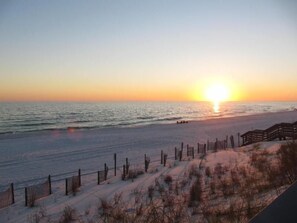 A beach with a wooden fence and a sunset.