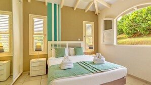 Une chambre à coucher avec un lit, des tables de chevet et une fenêtre donnant sur un paysage verdoyant.