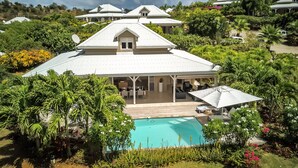Une grande maison avec une piscine, entourée d’une végétation luxuriante.