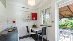 A modern kitchen with white cabinets, a red fridge, and a dining area with two chairs and a table. - Apartment in Umag with Terrace, Air condition, WIFI, Washing machine (244-3) (Umag)