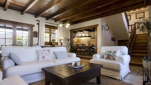 Amplia sala de estar con un sofá blanco, una mesa de centro de madera y una escalera que sube a un nivel superior.