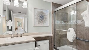 A modern bathroom with a glass shower enclosure, a large mirror, and a framed artwork on the wall. - Partial Beach View 2 bed, 2 bath at Sanibel Moorings #732 (Sanibel)