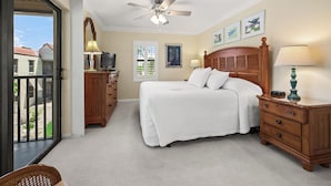 A bedroom with a bed, a ceiling fan, a TV, a dresser, and a window with a view. - Partial Beach View 2 bed, 2 bath at Sanibel Moorings #732 (Sanibel)