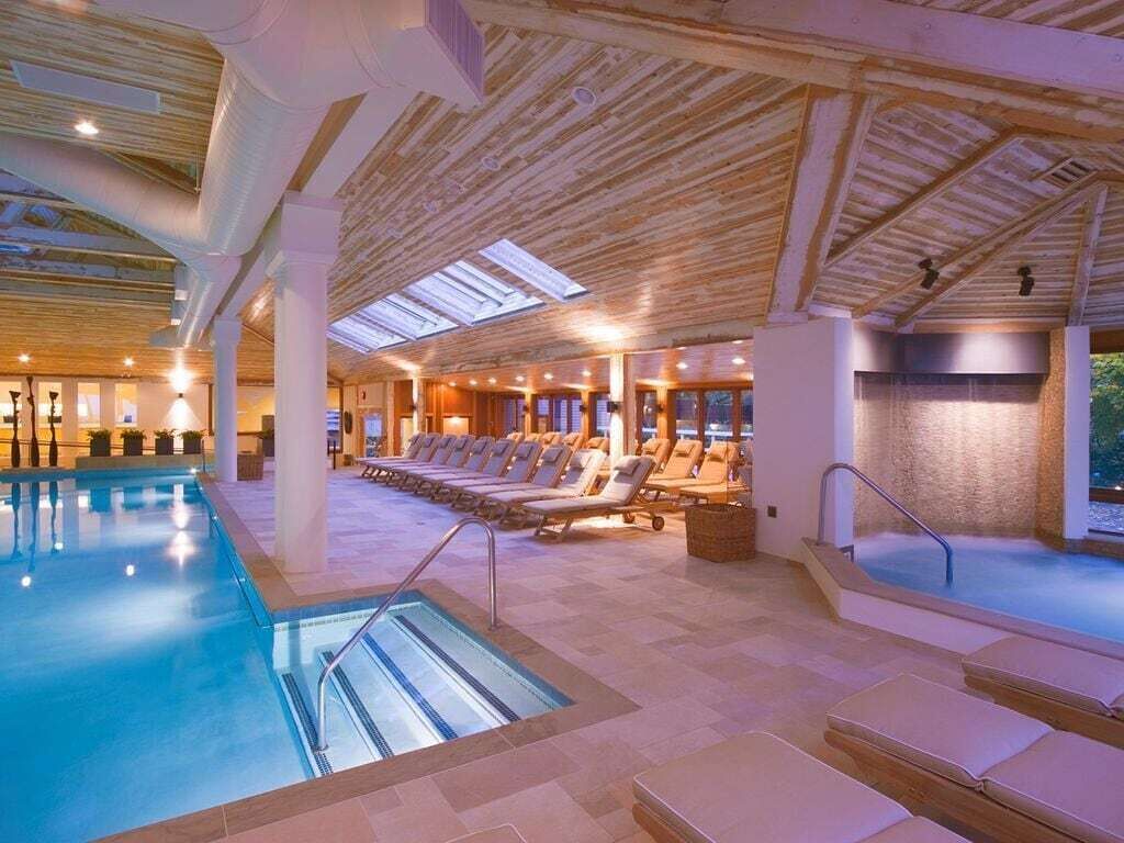 A swimming pool area with lounge chairs and a stone wall.