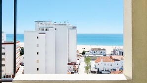 A view of a coastal town with a prominent white building in the foreground, a beach, and clear blue skies.