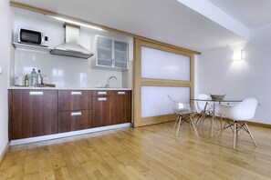 A modern kitchen with wooden cabinets, a microwave, and a dining area with a glass table and white chairs. - El Estudio de Lela, Your very home in the heart of Arrecife (Arrecife)