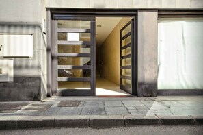 A building entrance with a large glass door, a visible mailbox, and a concrete pavement. - El Estudio de Lela, Your very home in the heart of Arrecife (Arrecife)