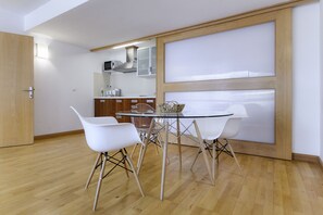 A modern kitchen with white cabinets, a microwave, and a glass-top dining table with four white chairs. - El Estudio de Lela, Your very home in the heart of Arrecife (Arrecife)