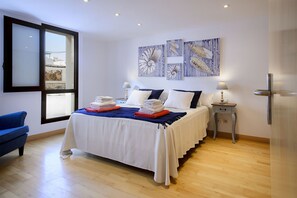 A bedroom with a bed, a blue chair, a nightstand, and artwork on the wall. - El Estudio de Lela, Your very home in the heart of Arrecife (Arrecife)