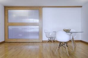 A room with a sliding glass door, a glass table, and four white chairs.