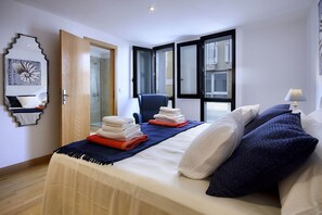 A hotel room with a bed, towels, a chair, a lamp, and a view of the city through large windows. - El Estudio de Lela, Your very home in the heart of Arrecife (Arrecife)