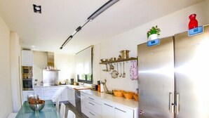 A modern kitchen with stainless steel appliances, a glass dining table, and a variety of kitchen utensils and cookware displayed on the wall. - Club Villamar - Fully detaches 8-persons vila, ideal for families at only 4 kilometers away from ... (Mont Ras)