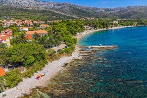Enjoy the picturesque beach with clear waters, surrounded by lush greenery and traditional buildings.