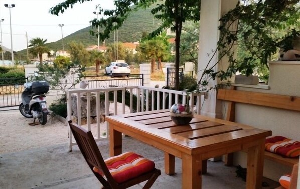 Relax in this serene outdoor seating area with a table and two comfortable chairs, surrounded by a picturesque view of the hilly landscape.