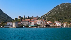 Una cittadina costiera con edifici storici, un castello e un mare cristallino.