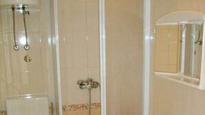 Une salle de bain comprenant des toilettes, un espace douche, un lavabo et un miroir.