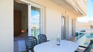 Een balkon met een witte tafel, twee stoelen en een fles champagne.