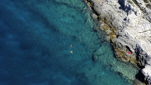 A coastal area with clear water, rocky terrain, and people swimming and sunbathing. - Apartment in Medulin with Terrace, Air condition, WIFI, Washing machine (64-3) (Medulin)