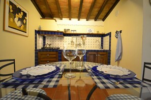 Mesa de jantar posta com toalhas xadrez azul e branco, duas taças de vinho e pratos.