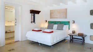 Un dormitorio con cama, una mesita de noche, un mapa en la pared y un baño visible a través de una puerta abierta.