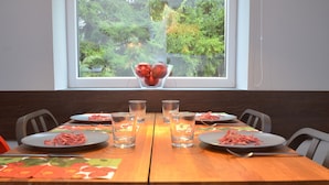 Una mesa de comedor con platos de comida, vasos y un frutero en el alféizar de una ventana.