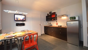 Cocina compacta con comedor, televisor de pantalla plana, microondas y refrigerador.