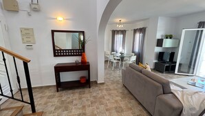 Un salon avec un canapé, une table à manger et des chaises, un téléviseur et un escalier.