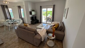 Un salon comprenant un canapé, une table basse, un téléviseur et un coin repas avec des chaises et une table.