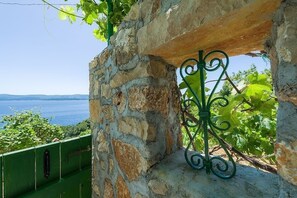 Stroll through a lush vineyard, surrounded by a historic stone wall and a picturesque view of a serene body of water.