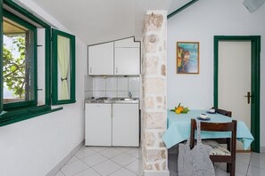 Cozy dining area with a table for two, sink, and a painting on the wall.