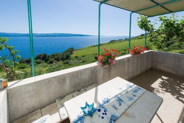 A terrace with a view of the sea, a table with a blue and white tablecloth, and potted plants. - Apartment in Murvica with Seaview, Terrace, Air condition, WIFI (146-4) (Murvica)
