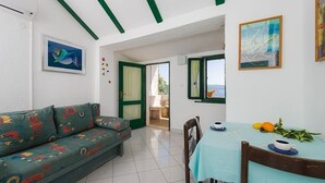 A room with a sofa, a table with cups and lemons, and a painting on the wall. - Apartment in Murvica with Seaview, Terrace, Air condition, WIFI (146-4) (Murvica)