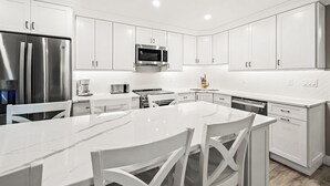 Una cocina moderna con armarios blancos, electrodomésticos de acero inoxidable y encimera de mármol.
