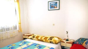 Een slaapkamer met een bed, nachtkastje, lamp en een ingelijst kunstwerk aan de muur.