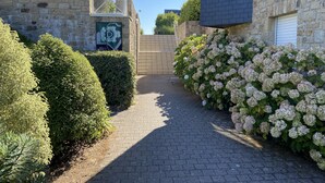 Un chemin pavé mène à un bâtiment aux murs de pierre et doté d’une fenêtre en verre.