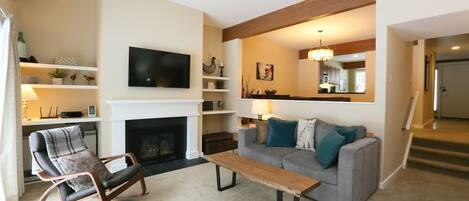 A living room with a fireplace, a television, a sofa, and a rocking chair.