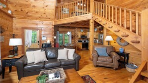 A wooden cabin interior with a living room, dining area, kitchen, and a wooden staircase. - Shady Lady Cabin in The Smokies with Beautiful Views, Just 5 miles from Town (Sevierville)