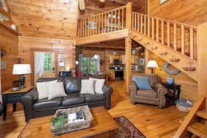 A wooden cabin interior with a living room, dining area, kitchen, and a wooden staircase. - Shady Lady Cabin in The Smokies with Beautiful Views, Just 5 miles from Town (Sevierville)