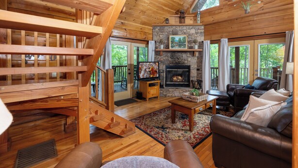 A wooden interior with a fireplace, leather sofa, and a staircase. - Shady Lady Cabin in The Smokies with Beautiful Views, Just 5 miles from Town (Sevierville)