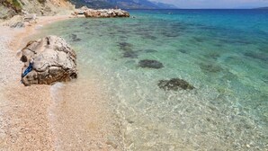 A clear beach with rocky outcrops and a pebble beach.
