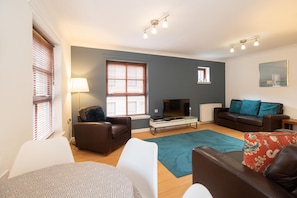 Relax in this stylish living room with a brown leather sofa, armchair, and flat-screen TV.