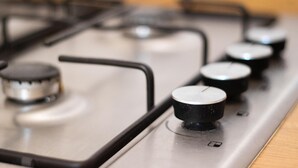 Een detailopname van een gasfornuis met vier knoppen en een bedieningspaneel.