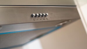 Een close-up van een metalen bedieningspaneel met meerdere knoppen en een draaiknop.