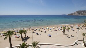 A beach with numerous umbrellas and palm trees, a clear sky, and a distant mountain. - A59 CALPEMAR A 5º 18 (Calpe)