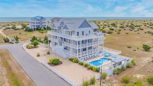 Une propriété en bord de mer, composée de plusieurs étages, dotée d’une piscine et d’un espace extérieur aménagé pour se détendre.
