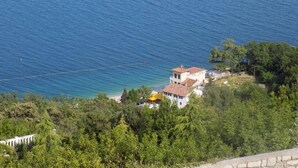 Ein Küstengebiet mit einem weißen Gebäude, einem Strand und üppiger Vegetation.