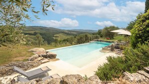 A swimming pool with a view of rolling hills, surrounded by rocks and greenery. - Villa in Lucarelli with 6 bedrooms sleeps 10 (Lucarelli)