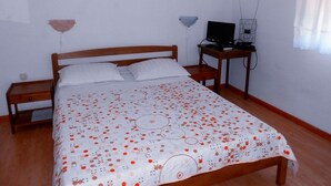 Une chambre à coucher avec un lit en bois, un bureau avec un ordinateur et une lampe fixée au mur.